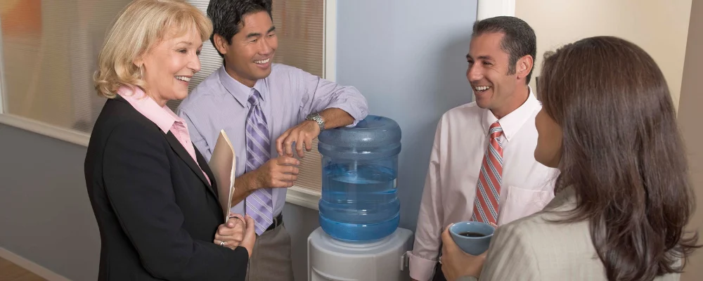 Coworkers chatting and laughing by the water cooler